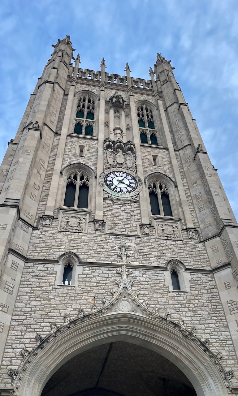 A stone university clock tower photographed from below.