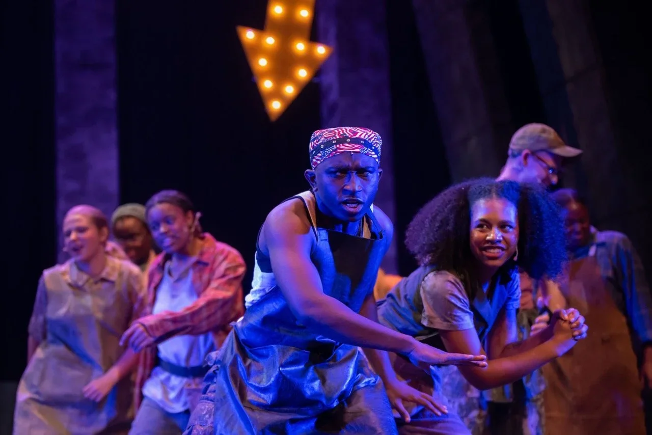Scene of Urinetown highlighting ensemble traffic through the set.