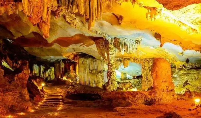 Illuminated cave interior with stalactites, stone steps, and glowing orange-yellow rock formations