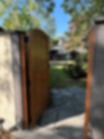 wooden gate opening onto a secluded back yard landscape with flagstone