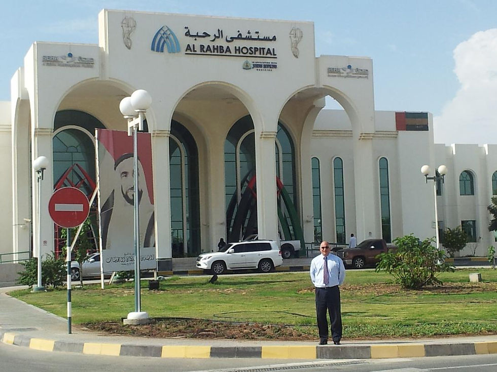 landscape photo of a man in business attire standing in front of Al Rahba Hospital in the UAE