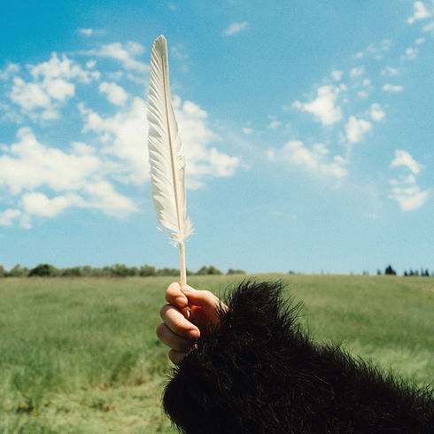 Holding a feather wearing a black feather jacket