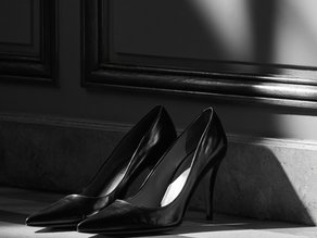Une paire d'escarpins noirs petite pointure à talons hauts posés sur le sol dans un décor chic.