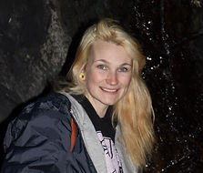 A happy nature loving woman with blonde hair and blue eyes, wearing a rain jacket, located in the blue ridge tunnel on a trip