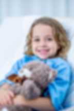 Young girl smiling in a hospital bed with teddy bear at Akron Children’s Hospital, representing Hart Communications annual donation efforts across Pennsylvania.