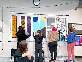 Teens painting a banner that says "Lumen"