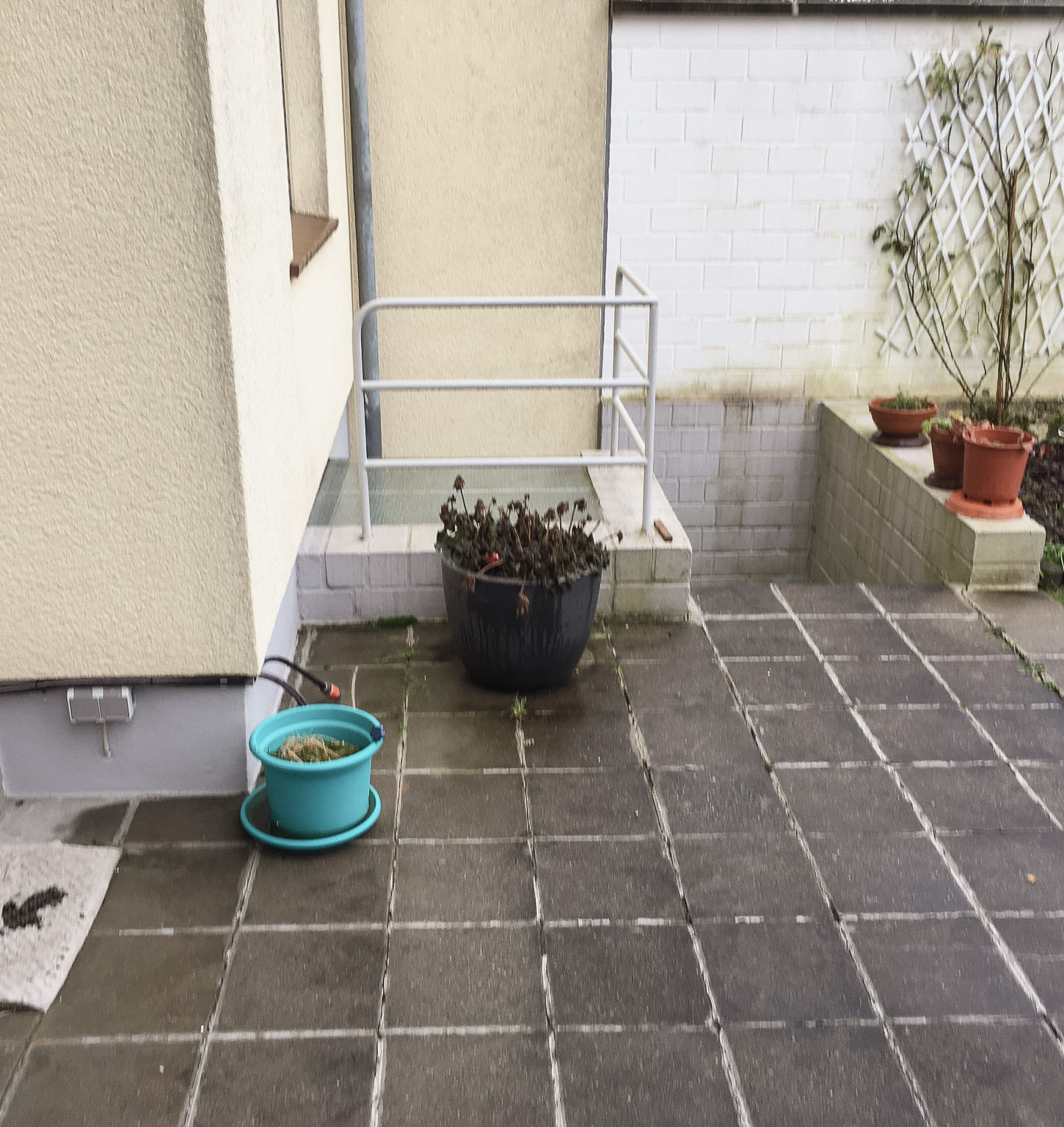 Kleine Terrasse aus Holz, Pflanzenkübeln und Gartenzaun