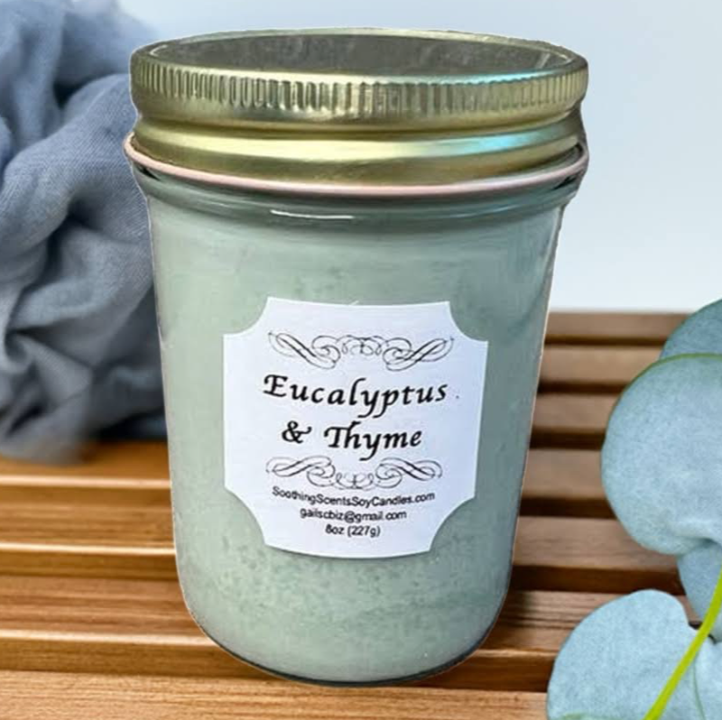 Sage green-color Eucalyptus & Thyme soy candle, 8oz, Jelly Jar, gold lid, white label shown on spa bench with bath sponge