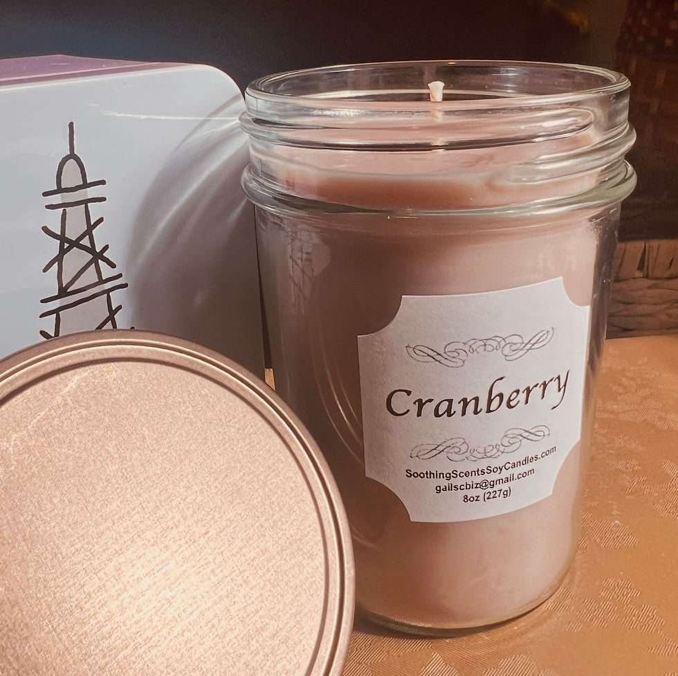 Light maroon colored cranberry soy candle in a classic jelly jar with rustic threaded lid. Sitting next to cute tin.