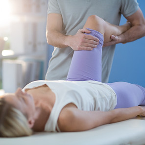 Male physiotherapist giving knee massage to female patient in clinic