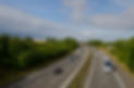 Traffic on the motorway with green trees and cloudy sky