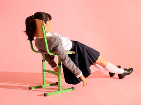 Frustrated dyslexic student wearing school uniform, slouching down in her desk to avoid being called on to do long division in front of the class.