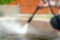 A person uses a pressure washer to clean a patio