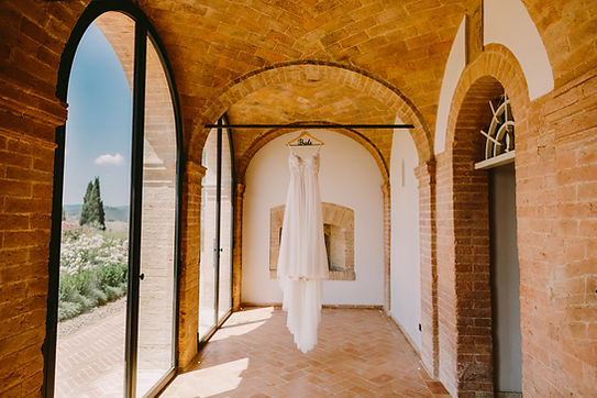 Elegantes Brautkleid hängt an einem Fenster – detailreiche Aufnahme für das Hochzeitsvideo, die die Vorfreude auf den großen Moment spürbar macht.