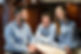 Three individuals in blue button-up shirts sitting around a marble countertop, engaged in conversation