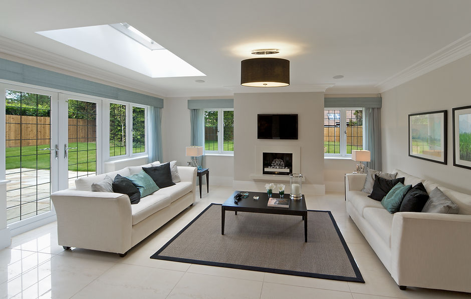 Spacious, modern living room with two white sofas, black coffee table, and a wall-mounted TV