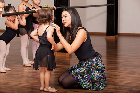 Young female dance instructor comforting one of her younger ballet students during a dance