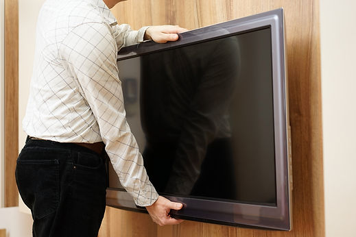 Technician carefully mounting flat screen television onto wall panel