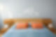 Close-up of a bed with clean orange-coloured pillows