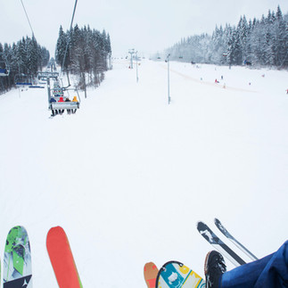 Tourists riding the Mount Hermon cable car with skis and snowboards over the white winter landscape.