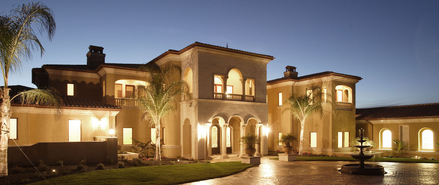 Luxurious residential estate at twilight with exterior lighting.