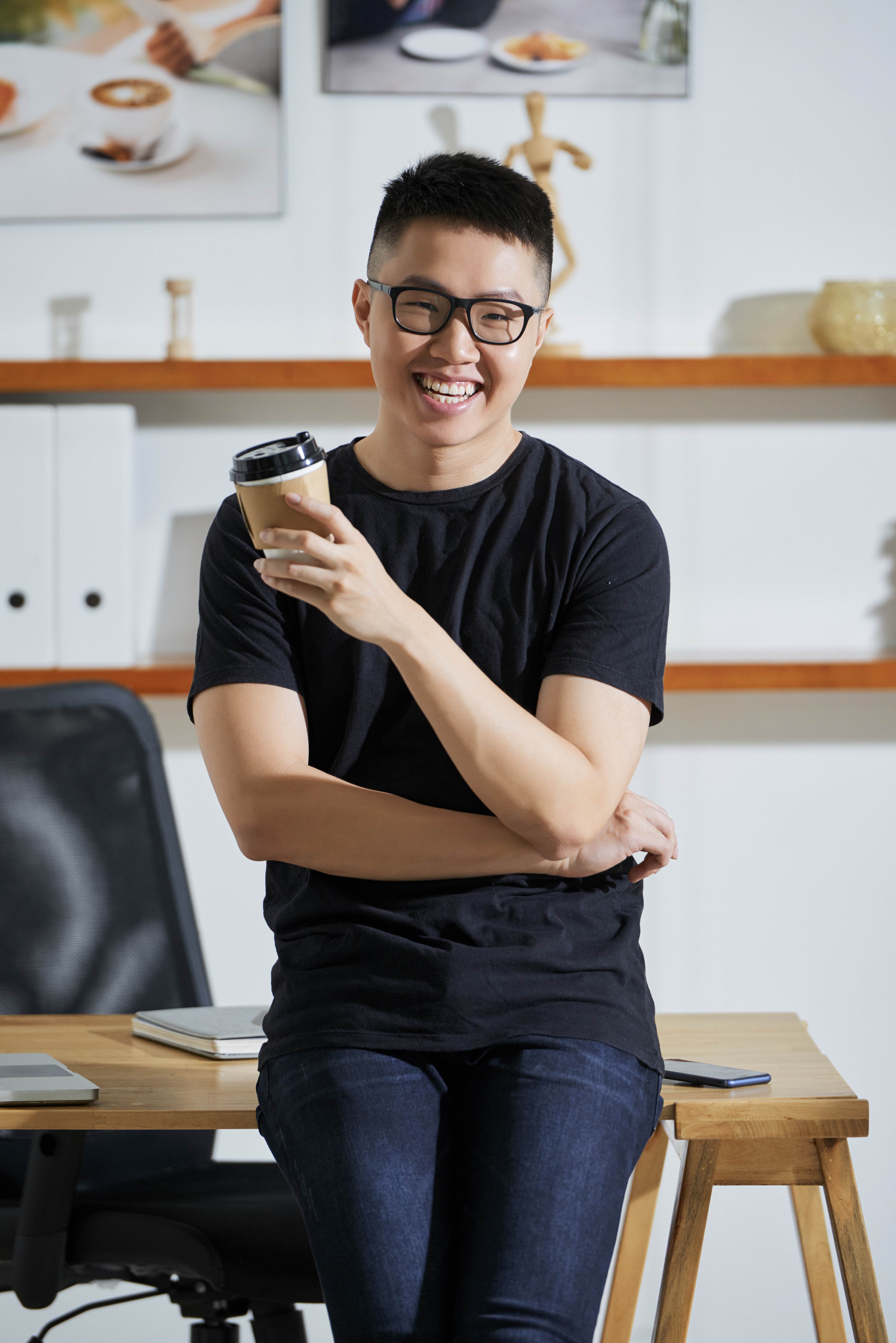 Asian man with glasses holding a coffee cup