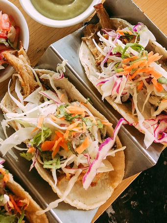 Three tacos with coleslaw, meat, salsa, and lime