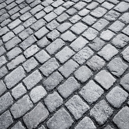 A monochrome, high-angle close-up of an old stone paved surface