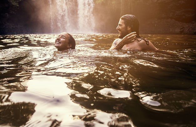 Couple Swimming and laughing in front of a waterfall