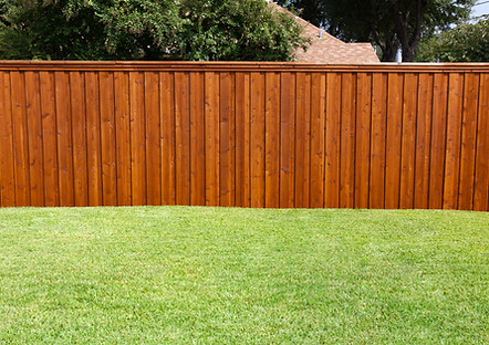 A stained wooden fence bordering freshly cut grass