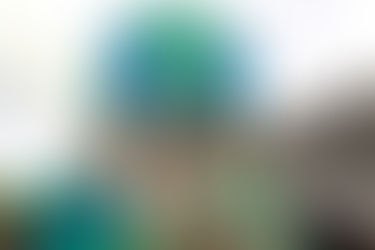 Hands raise a globe made from blue and green plastic, symbolizing environmental unity, set against a mountainous backdrop.