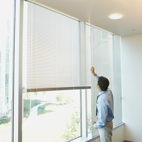 Businessman adjusting window blinds