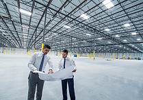 Architects examining blueprint in empty warehouse