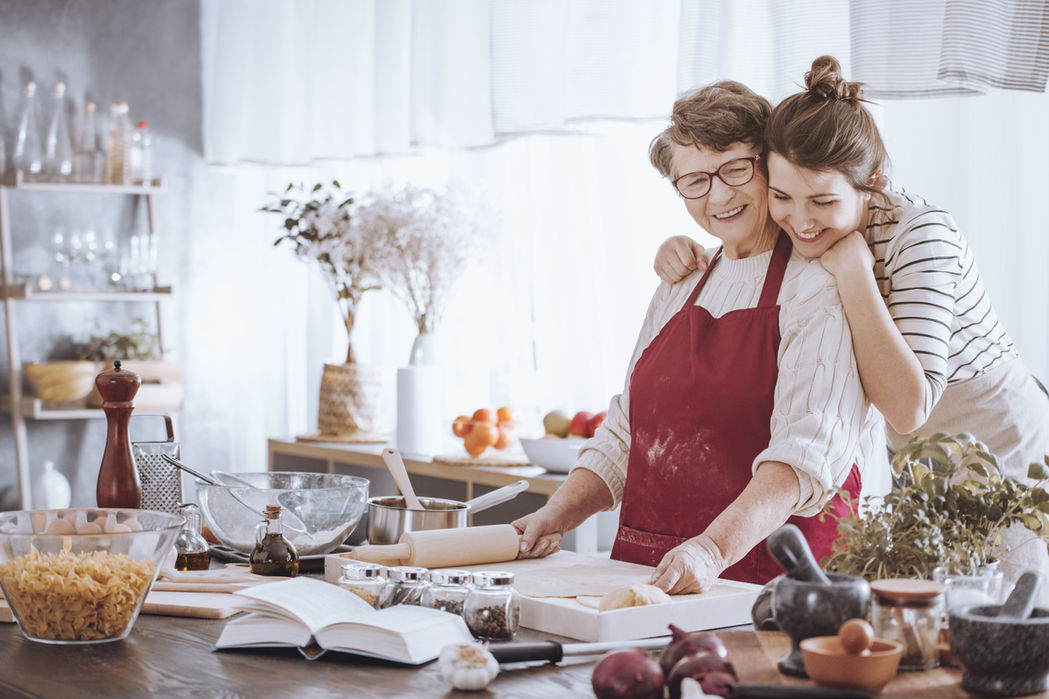Happy grandmother and granddaughter baking together in kitchen