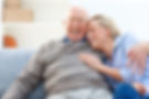 Loving senior man embracing his daughter while sitting on sofa smiling