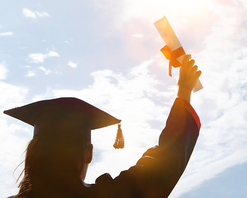 A graduate celebrating receiving her diploma by raising it in the air victoriously