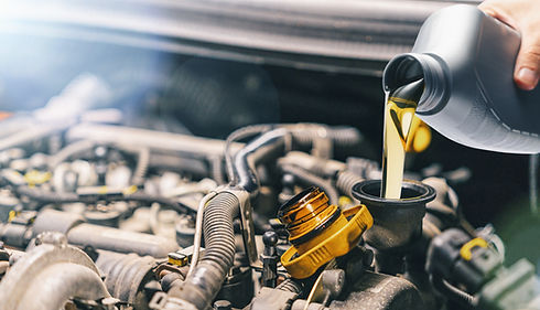 Close-up of a hand pouring motor oil into a car engine