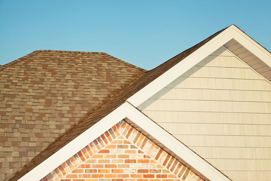 Steel and Brick Sided House Roof Peaks against Blue Sky