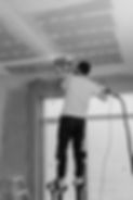 Worker sanding ceiling on stilts