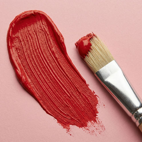 a smear of red paint next to a paint brush