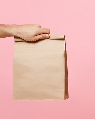 Hand, die braune Papiertüte hält