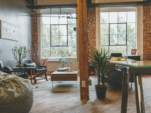Sunlit loft living room with exposed brick walls, large windows, and minimalist furniture — a serene, quiet luxury home interior.