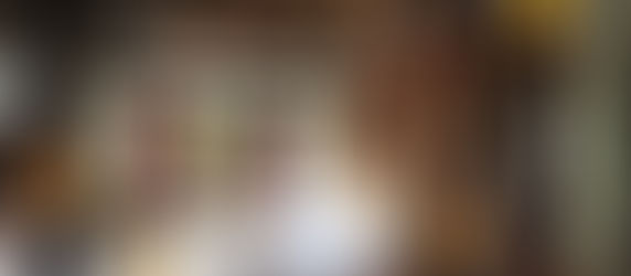 Tropical bedroom with woven decor, white bed, wooden accents, warm lighting, and sliding doors open to a lush green balcony view.