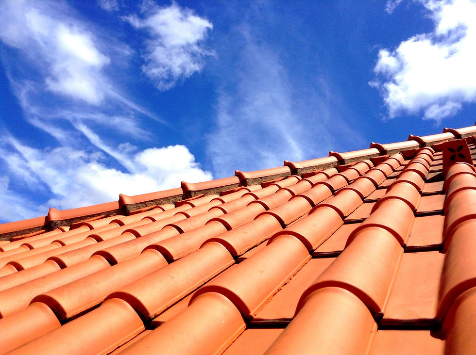 Bright orange terracotta roof tiles against a blue sky with clouds