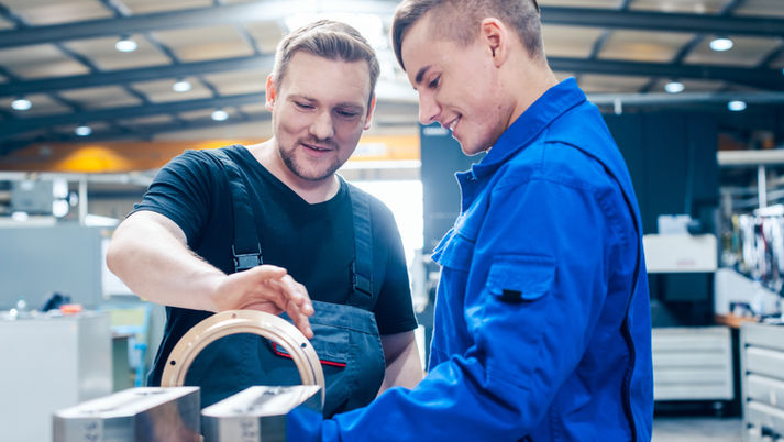 Young male apprentice being helped by a happy older man