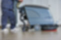 Operator using a large industrial floor scrubbing machine in a commercial space