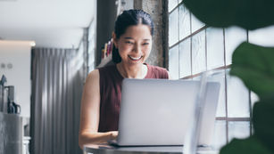 Smiling Women using laptop by large window