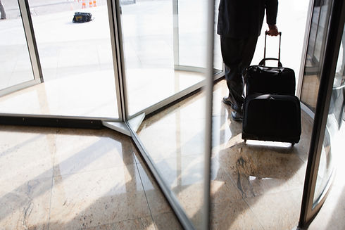 Businessman with suitcase using revolving door