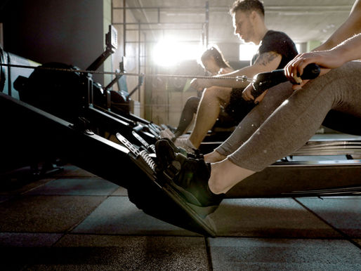 Athletes rowing on a machine during a HYROX training session in Boston.