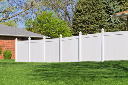 Bright white fence with finials dividing green lawn from houses.